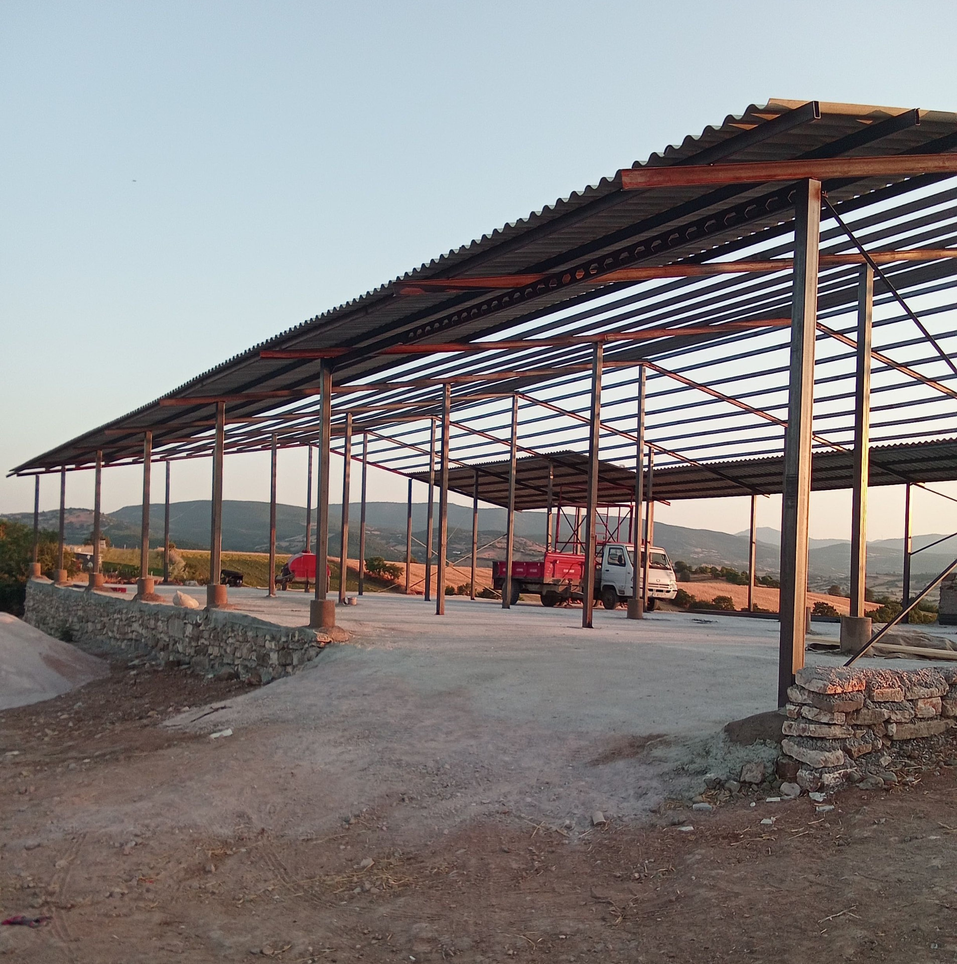 Metal kolonlar ve çapraz destekler üzerine oluklu levha kaplaması yapılan geniş çelik çatı