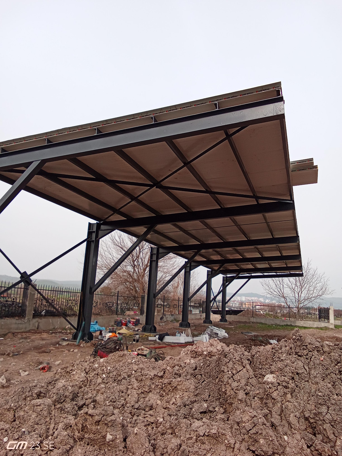 Siyah çelik kolon ve çaprazlar üzerine kurulu, panel kaplamalı konsol çıkmalı sundurma