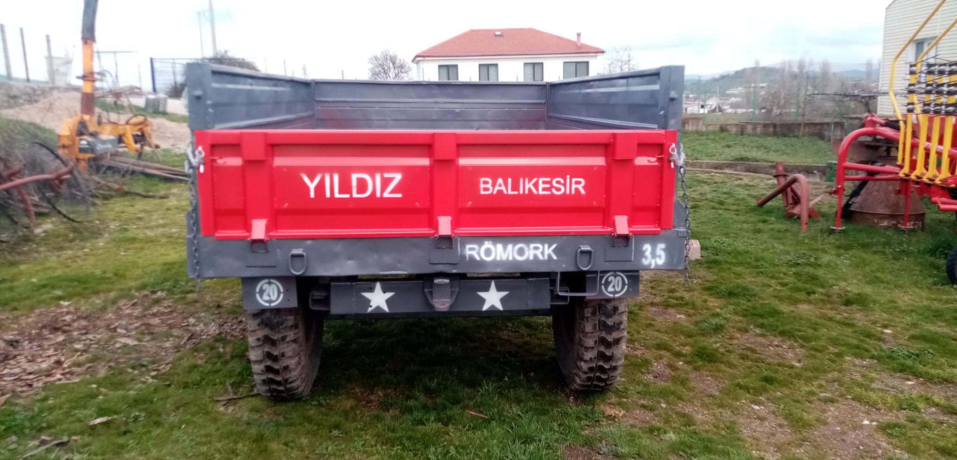 Kırmızı kasalı, gri kenarlıklı ve arka tamponunda yıldız işareti bulunan devrilmeli tarım römorku